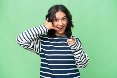 Arjantinli genç bir kadın izole edilmiş arka planda telefon hareketi yapıyor ve ön tarafı işaret ediyor.