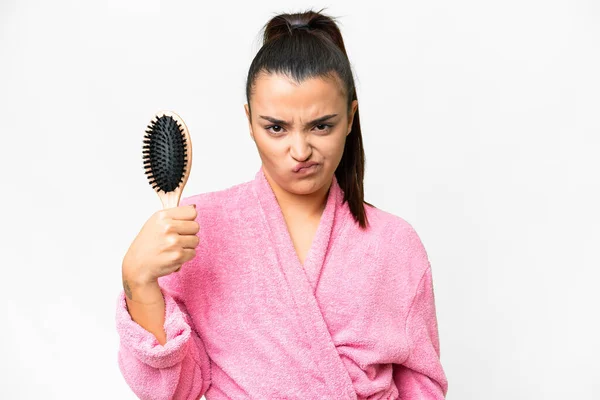 Young woman in a bathrobe with hair comb over isolated white background with sad expression