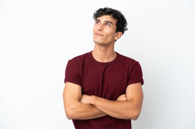 Genç Arjantinli adam beyaz arka planda izole edilmiş gülümserken yukarı bakıyor