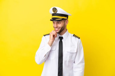 Kafkasyalı uçak pilotu sarı arka planda izole edilmiş, yan tarafa bakıyor.