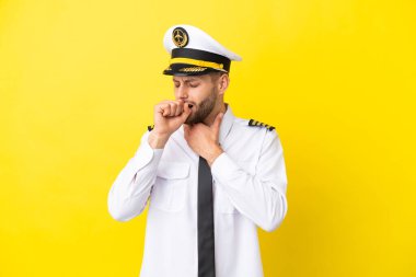 Sarı arka planda izole edilmiş beyaz uçak pilotu öksürükten muzdarip ve kötü hissediyor.