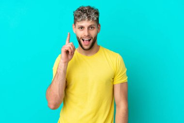 Genç, beyaz, mavi arka planda izole edilmiş genç bir adam bir fikir düşünüyor.