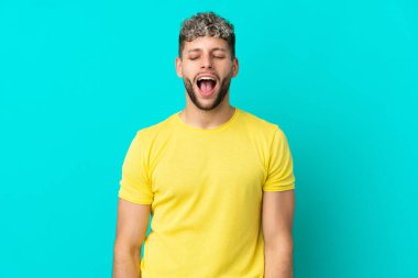 Mavi arka planda izole edilmiş, ağzı açık genç beyaz bir adam ön tarafa doğru bağırıyor.