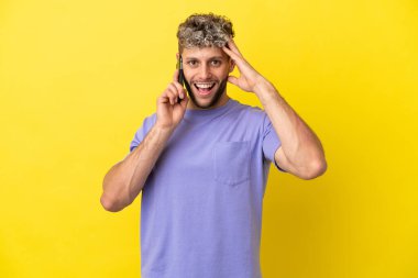 Sarı arka planda izole edilmiş cep telefonu kullanan genç, beyaz bir adam.