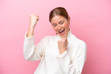 Young caucasian woman isolated on pink background celebrating a victory clipart