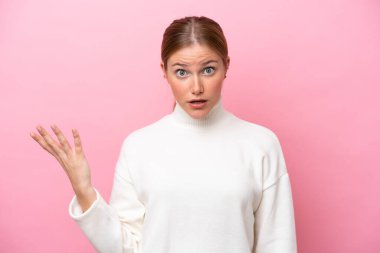 Pembe arka planda izole edilmiş genç beyaz kadın şüpheli hareketler yapıyor.