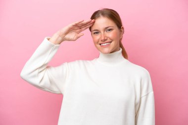 Pembe arka planda izole edilmiş beyaz bir kadın. Mutlu bir ifadeyle selamlıyor.