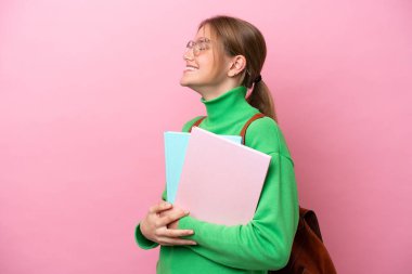 Pembe arka planda izole edilmiş beyaz bir kadın öğrenci yan yana gülüyor.