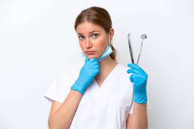 Beyaz arka planda izole edilmiş aletler tutan beyaz dişçi kadın.