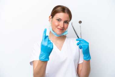 Beyaz arka planda izole edilmiş aletleri elinde tutan beyaz dişçi kadın geliyor.