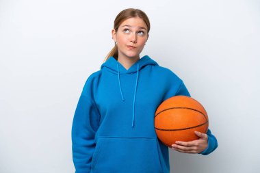 Basketbol oynayan beyaz tenli genç bir kadın beyaz arka planda izole edilmiş ve yukarı bakıyor.