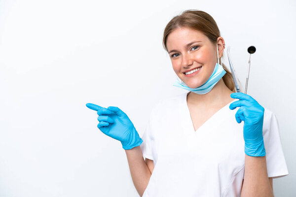 Dentist caucasian woman holding tools isolated on white background pointing finger to the side