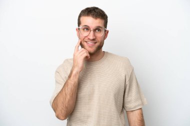 Beyaz arka planda izole edilmiş genç beyaz adam yukarı bakarken bir fikir düşünüyor.