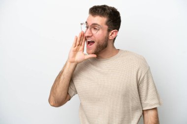 Beyaz arka planda izole edilmiş genç beyaz adam ağzı sonuna kadar açık bağırıyor.