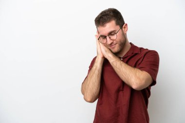 Beyaz arka planda izole edilmiş genç beyaz bir adam uyku jesti yapıyor.