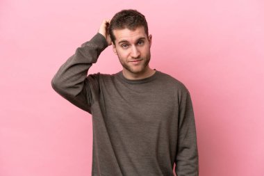 Pembe arka planda izole edilmiş genç beyaz bir adam hayal kırıklığı ifadesi ve anlamama.