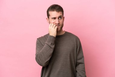 Pembe arka planda izole edilmiş genç beyaz adam biraz gergin.