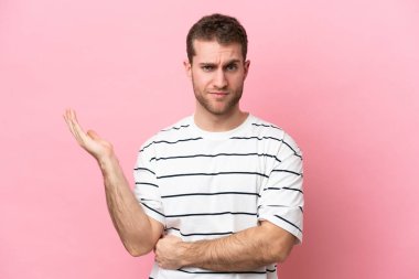 Pembe arka planda izole edilmiş genç beyaz adamın şüpheleri var.