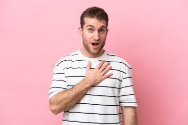 Pembe arka planda izole edilmiş genç beyaz adam sağa bakarken şaşırdı ve şok oldu.