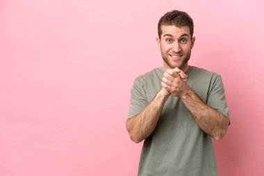 Pembe arka planda izole edilmiş genç beyaz adam gülüyor.
