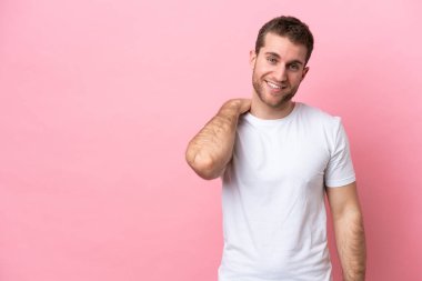 Pembe arka planda izole edilmiş genç beyaz adam gülüyor.