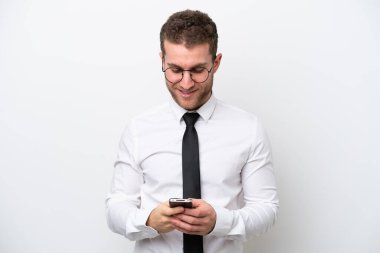 Beyaz arka planda izole edilmiş genç bir beyaz adam cep telefonuyla mesaj gönderiyor.