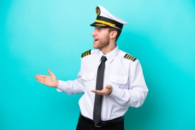 Kafkasyalı uçak pilotu mavi arka planda şaşırmış bir yüz ifadesiyle izole edildi.