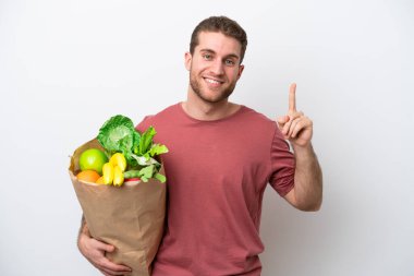 Beyaz arka planda izole edilmiş alışveriş torbası tutan beyaz bir adam harika bir fikre işaret ediyor.