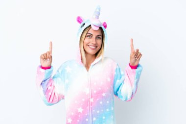 Beyaz arka planda izole edilmiş tek boynuzlu at pijaması giyen sarışın Uruguaylı kız harika bir fikre işaret ediyor.