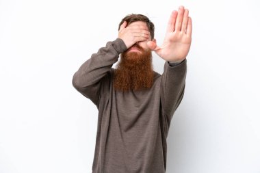 Beyaz arka planda sakallı kızıl saçlı adam jesti durdurup yüzünü kapatıyor.