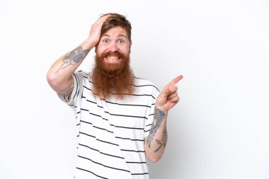 Beyaz arka planda sakallı kızıl saçlı adam şaşırdı ve parmağını yana çevirdi.