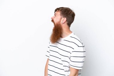 Beyaz arka planda sakallı kızıl saçlı adam yan yana gülüyor.