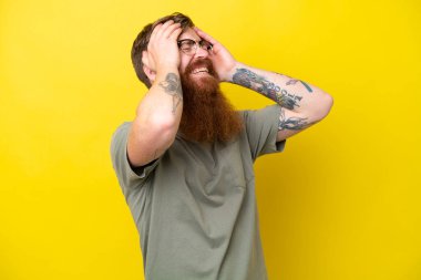 Sarı arka planda sakallı kızıl saçlı adam gülüyor.