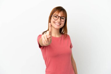 Kızıl saçlı kız beyaz arka planda izole edilmiş ve parmağını kaldırıyor.