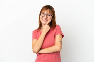 Kızıl saçlı kız beyaz arka planda yalnız mutlu ve gülümsüyor.