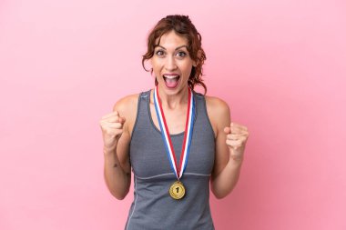 Pembe arka planda madalyalı beyaz bir kadın galibiyetini kutluyor.