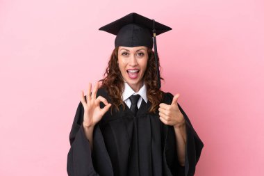 Üniversiteden mezun genç bir kadın pembe arka planda izole edilmiş.