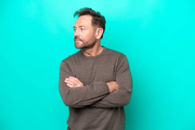 Orta yaşlı, beyaz bir adam mavi arka planda izole edilmiş.