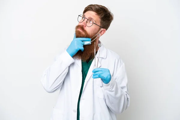 Dentysta Rudawy Mężczyzna Trzyma Narzędzia Izolowane Białym Tle Mając Wątpliwości — Zdjęcie stockowe