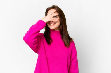 İzole edilmiş beyaz arka planda genç beyaz bir kadın. Gözleri kapalı ve gülümsüyor.