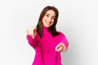 İzole edilmiş beyaz arka planda genç beyaz kadın gülümserken seni işaret ediyor.