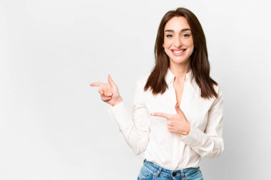 İzole edilmiş beyaz arka planda genç beyaz bir kadın parmak göstererek bir ürün sunuyor.