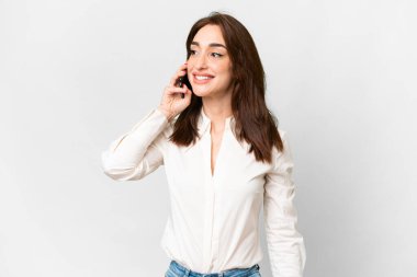 İzole edilmiş beyaz arka planda genç beyaz kadın cep telefonuyla sohbet ediyor.