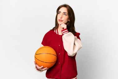 Genç basketbolcu kadın izole edilmiş beyaz arka planda gülümserken yukarı bakıyor