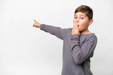 İzole edilmiş beyaz arka plan üzerinde küçük beyaz çocuk. Sürpriz bir ifadeyle işaret ederken...