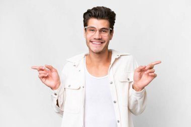 Soyutlanmış beyaz arka planda genç, yakışıklı, beyaz bir adam parmak uçlarında ve mutlu.