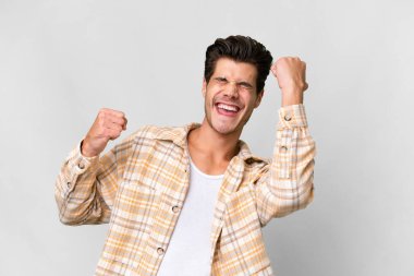 Soyutlanmış beyaz arka planda genç, yakışıklı beyaz adam zaferi kutluyor.