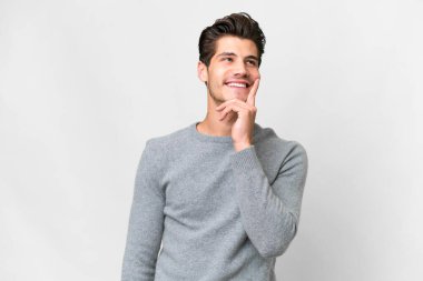 İzole edilmiş beyaz arka planı olan yakışıklı beyaz bir adam yukarı bakarken bir fikir düşünüyor.