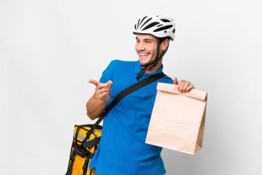 Kafkasyalı genç bir adam izole edilmiş arka planda bir çanta dolusu yiyecek alıyor. Parmakla göstererek bir ürün sunuyor.