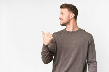İzole edilmiş beyaz arka planı olan yakışıklı beyaz bir adam bir ürün sunmak için kenarı işaret ediyor.